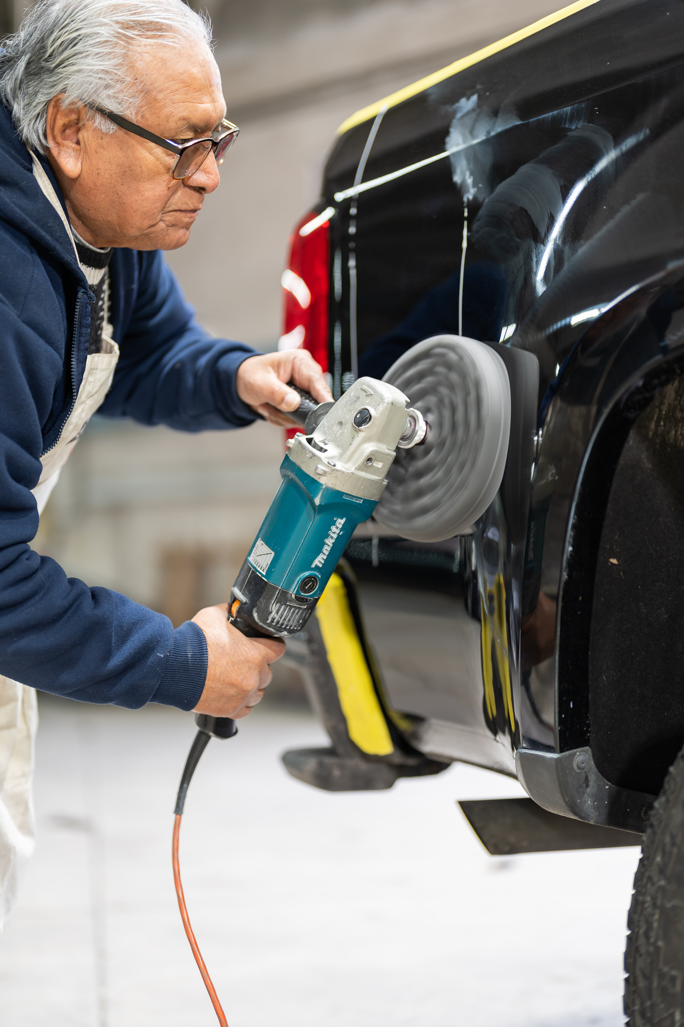 Paintless dent repair — precision buffing tool on black vehicle